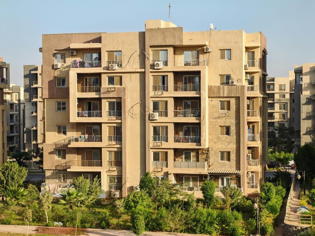 A modern apartment complex with greenery in a sunny urban environment.